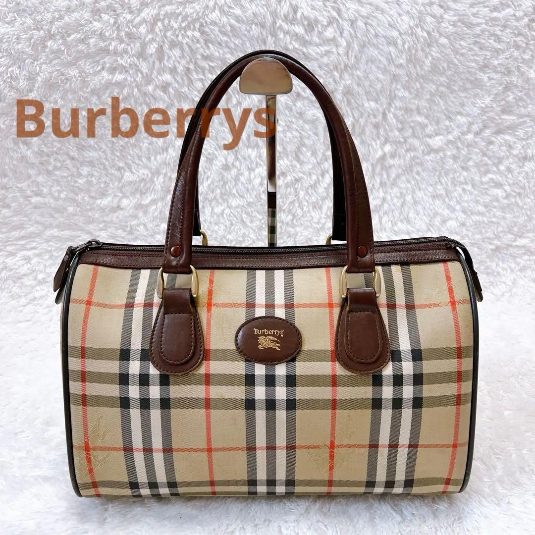 Front view of a Burberrys mini Boston bag in brown Nova check with leather handles displayed on a stand.