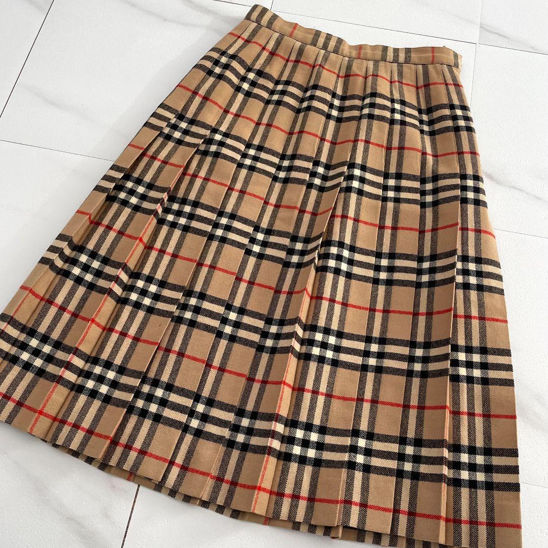 Beige Burberry Nova Check pleated skirt (size S) laid flat showing the waistband and pleats on a white tiled floor.