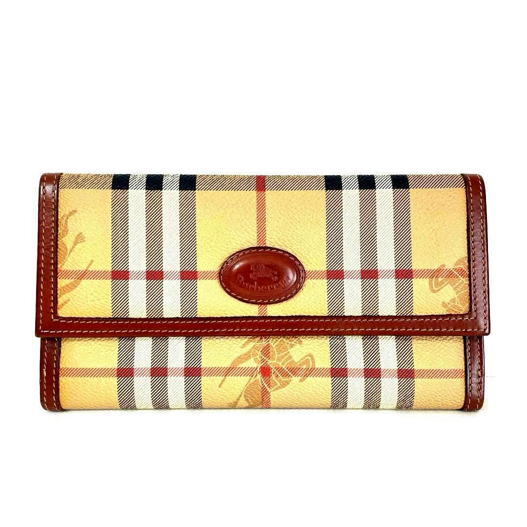 Front view of a PVC leather long wallet in Burberrys Nova check with brown leather trim and an oval logo on the flap.