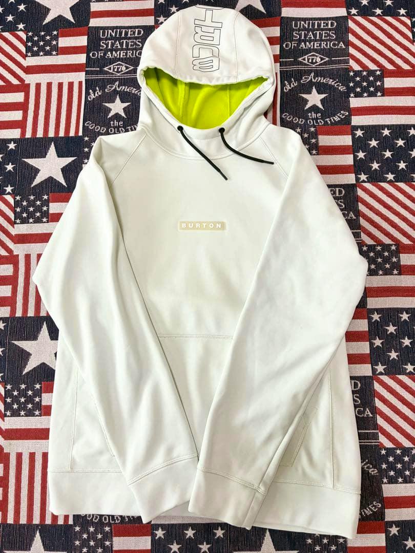 White BURTON water-repellent hoodie laid flat showing the chest logo and hood with vertical BURTON logo and lime-green lining.