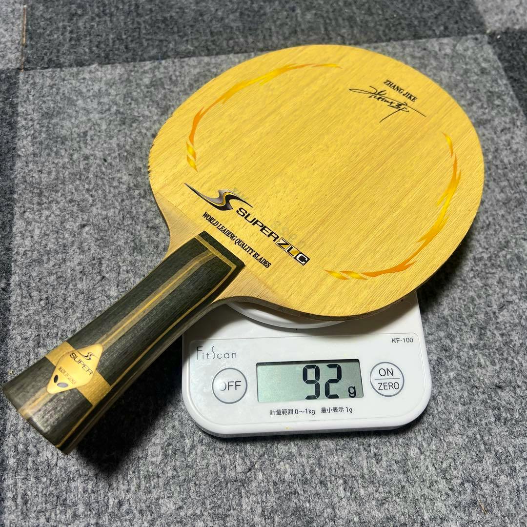 A Butterfly Zhang Jike Super ZLC table tennis racket blade and handle shown on a digital scale reading 92 g.