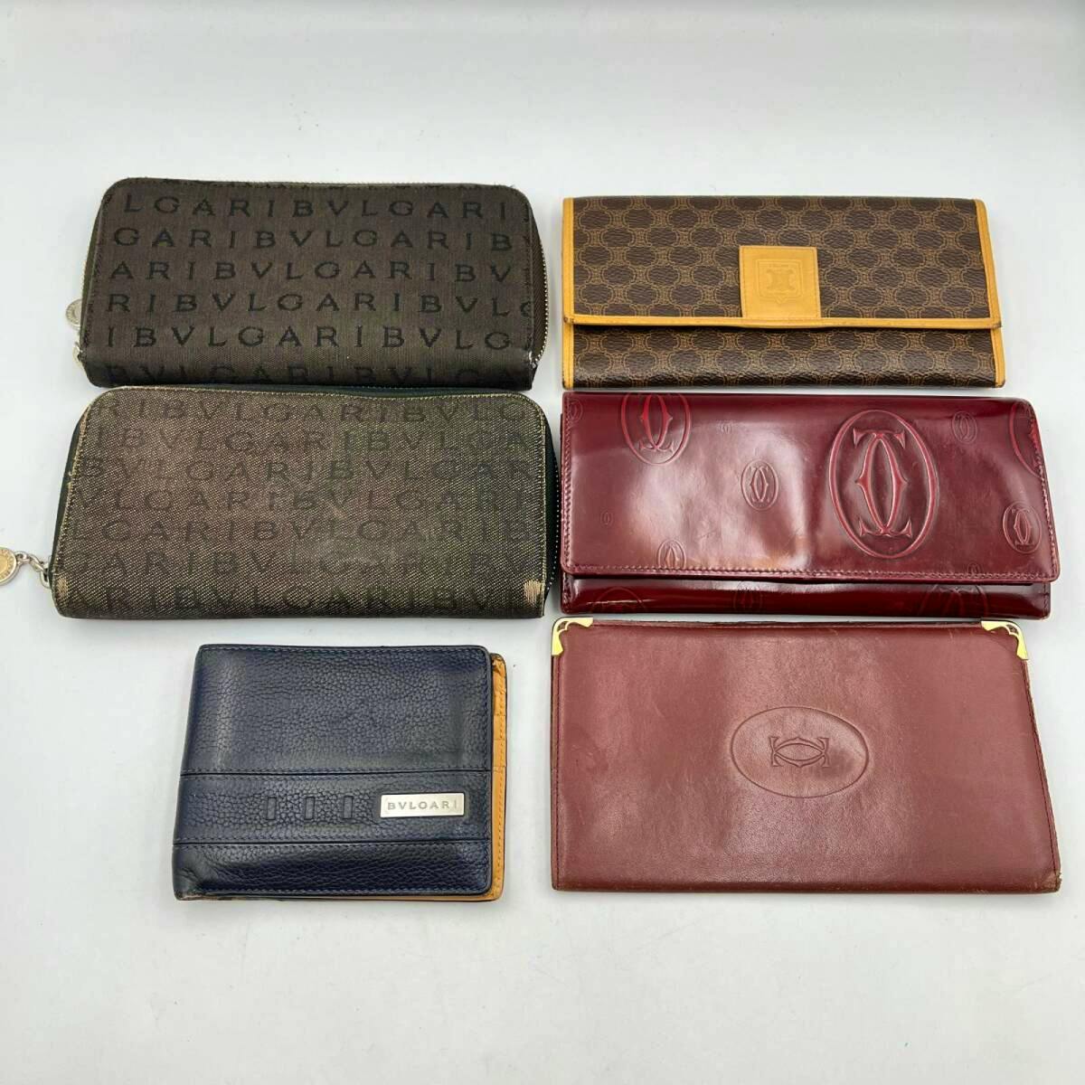 Six wallets of various brands laid flat on a white background, showing different patterns and a BVLGARI-branded wallet.