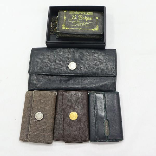 A set of five wallets and key holders, including a large black leather wallet and four smaller BVLGARI wallets, arranged on a white background.