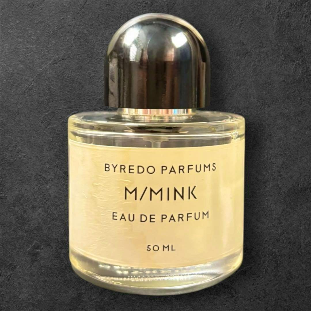 A BYREDO M/MINK 50ml perfume bottle with a black cap and label reading "M/MINK Eau de Parfum" on a dark textured background.