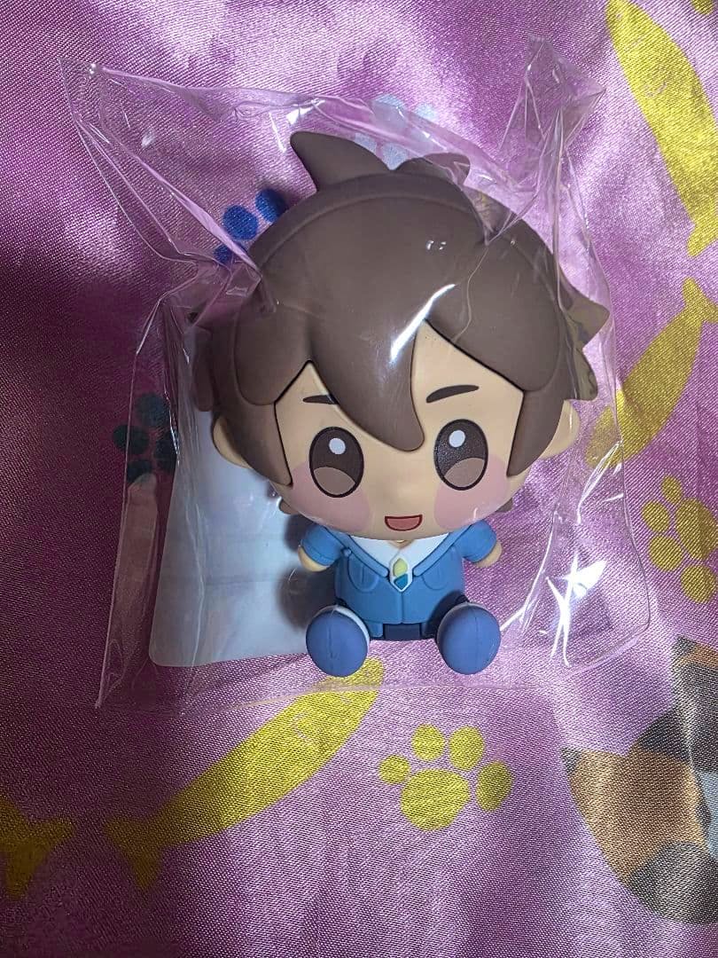 Photo of the C賞　エイト plastic figure in clear packaging on a pink fabric background.