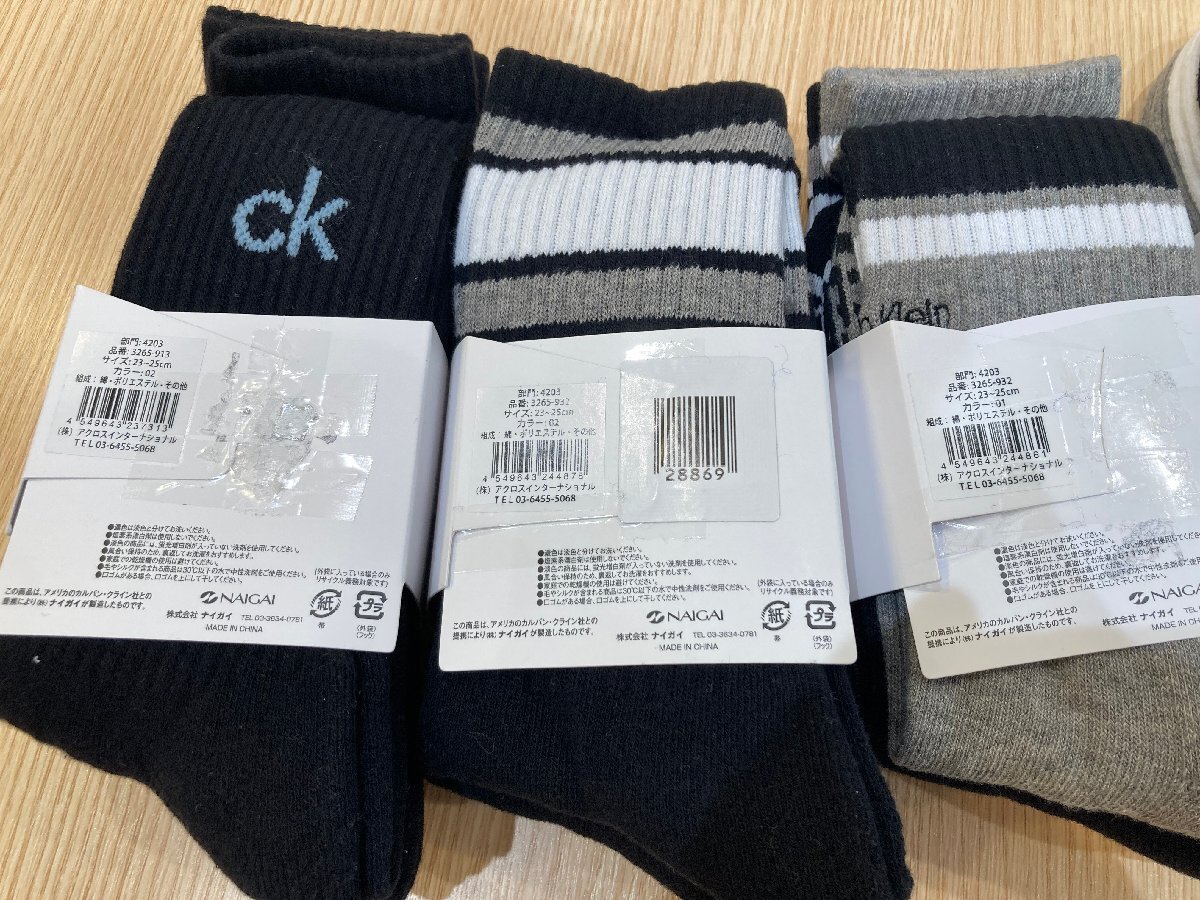 Close-up of three Calvin Klein socks with white paper bands and visible barcodes on a wooden surface.