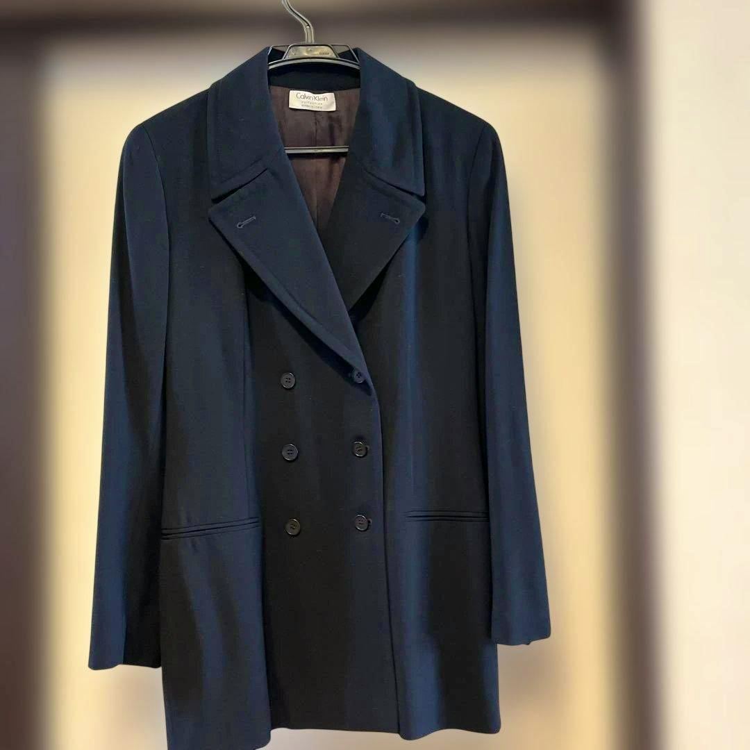 Front view of a navy Calvin Klein double-breasted jacket hanging on a hanger.