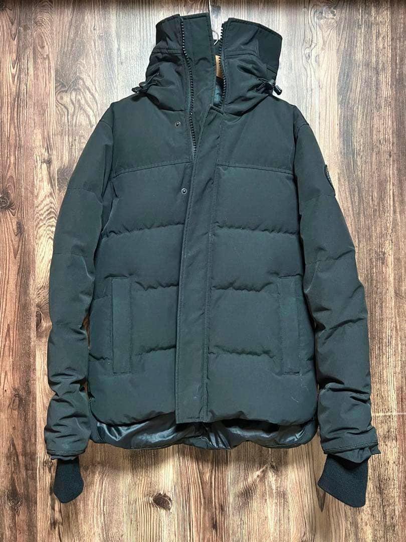 Front of the men's Canada Goose down jacket (XS) laid flat on a wooden floor.