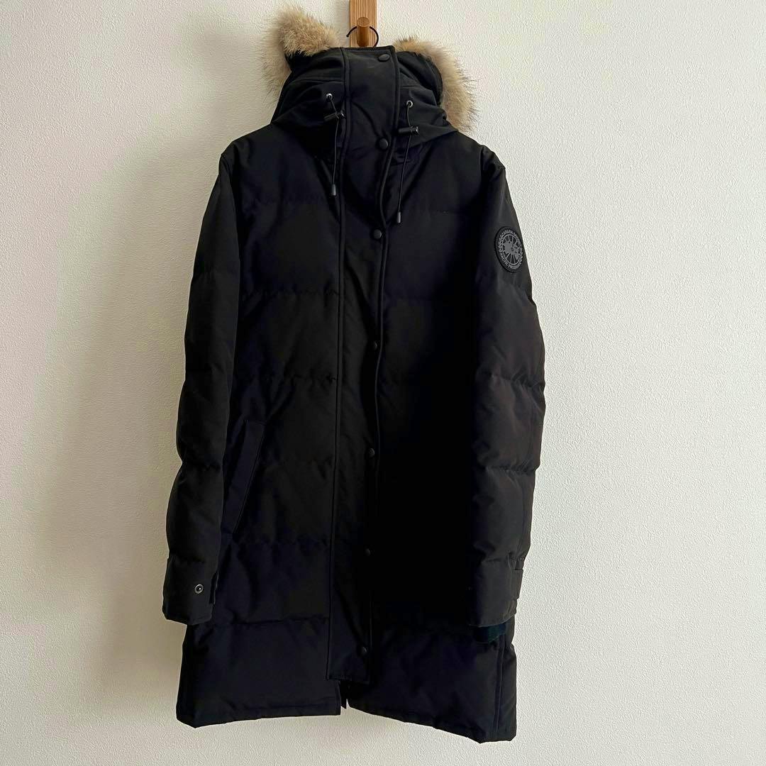 Front view of a black Canada Goose SHELBURNE parka for women hanging on a hook with hood and fur trim visible.