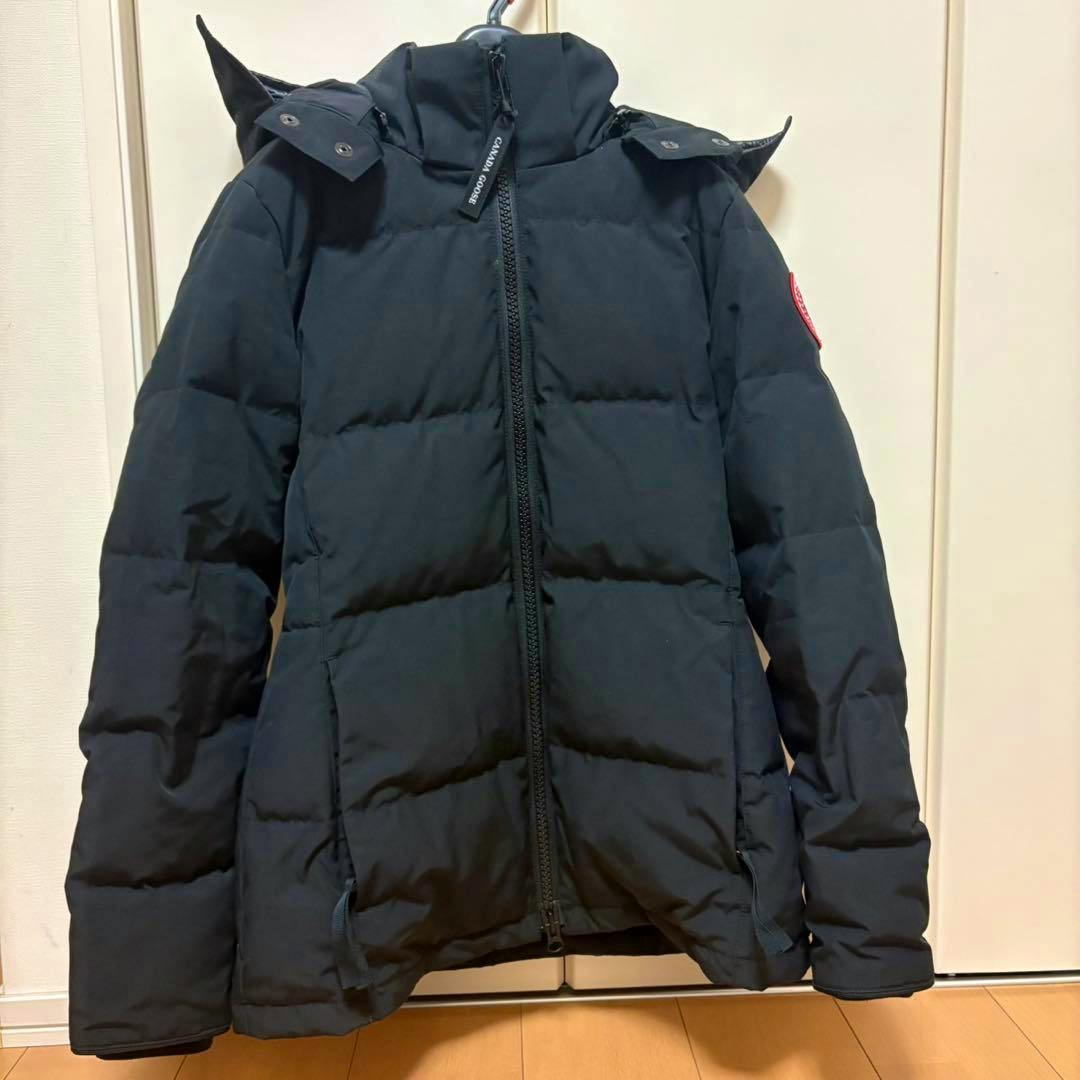 Front view of a black Canada Goose down jacket hanging on a hanger.