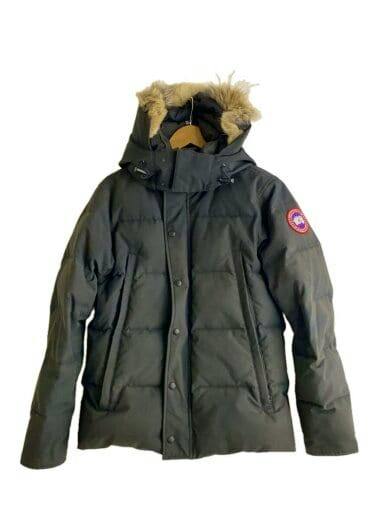 Front view of a black Wyndham parka down jacket with a fur-trimmed hood and a sleeve patch, hanging on a hanger.