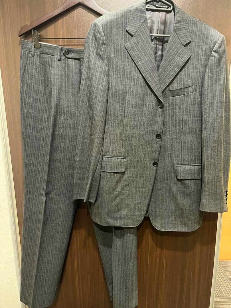 Charcoal-gray pure wool men's suit jacket with matching trousers hanging on hangers.