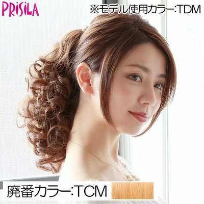 Side view of a model wearing the cream milk tea synthetic wig styled in tight curls (curly ponytail).