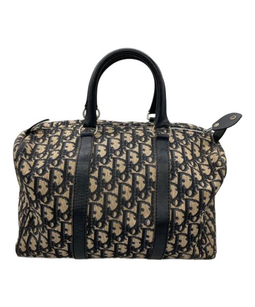 Mini Boston canvas bag with an all-over patterned fabric, black leather handles, and a zip-top closure.