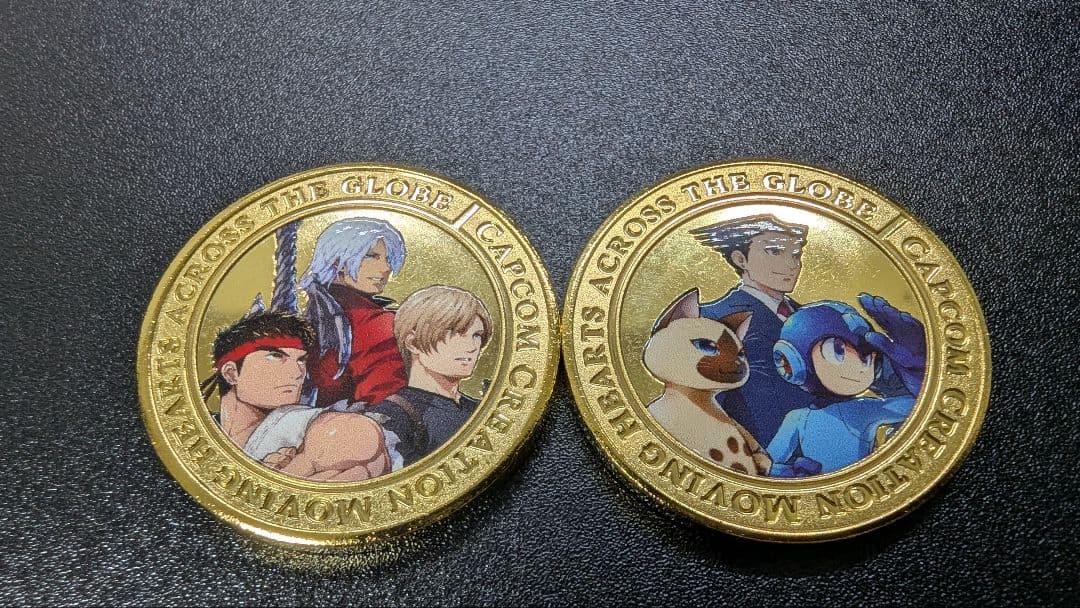 Two commemorative Capcom exhibition medals with colored character artwork on their faces.