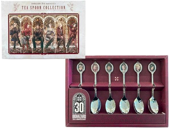 A boxed set showing six metal teaspoons with character portrait medallions in a burgundy Biohazard 30th Anniversary presentation box.