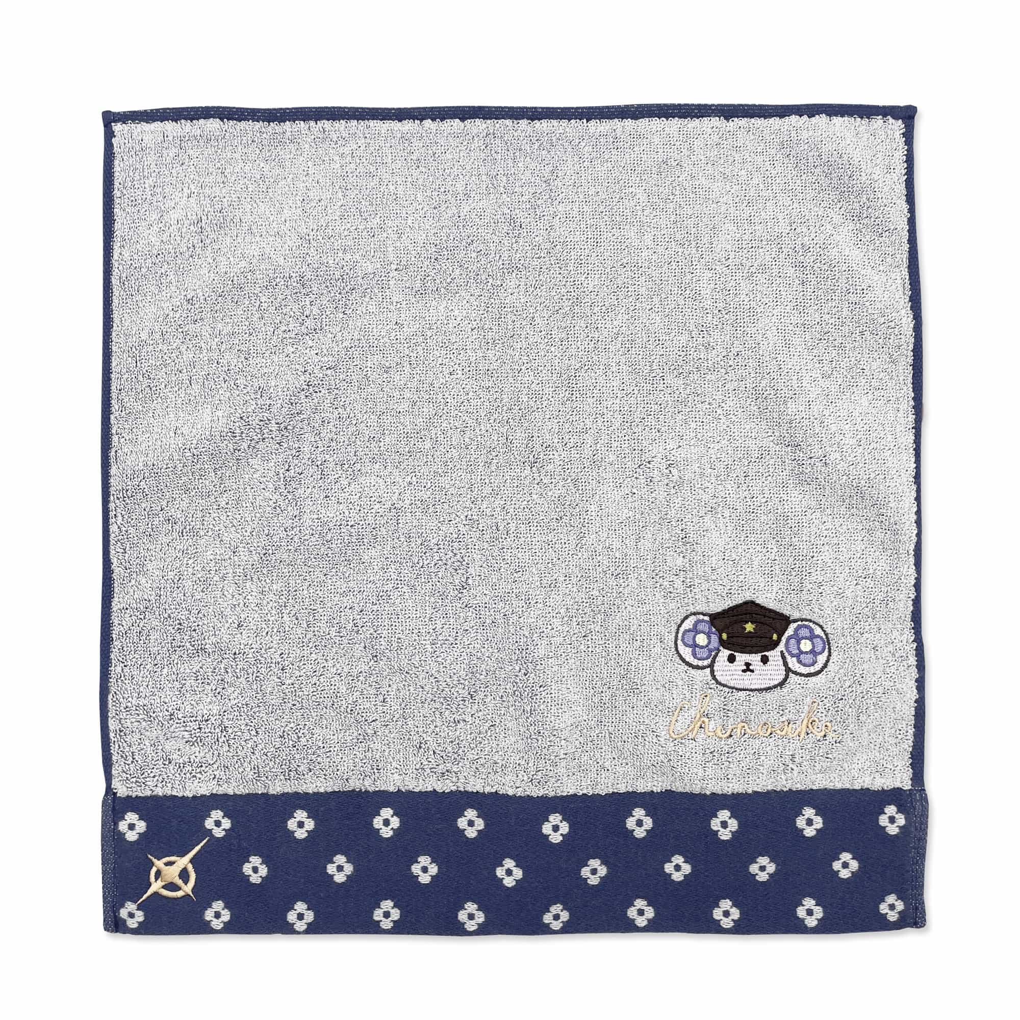 Square gray face towel with a navy patterned hem and a small embroidered character in the lower-right corner.