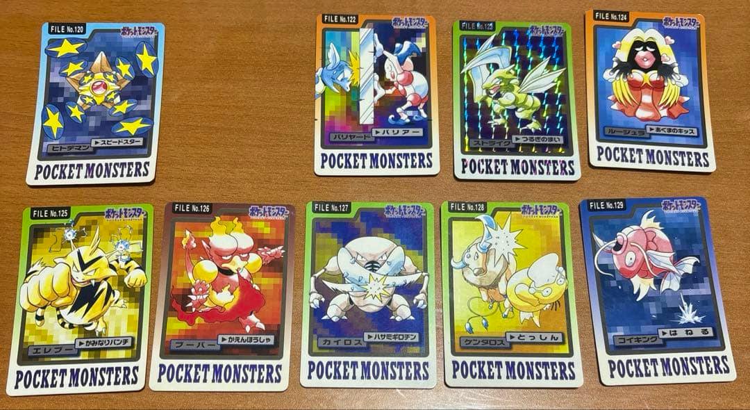 A set of ten Carddass Pocket Monsters trading cards (numbers 120–129) laid out on a wooden table.
