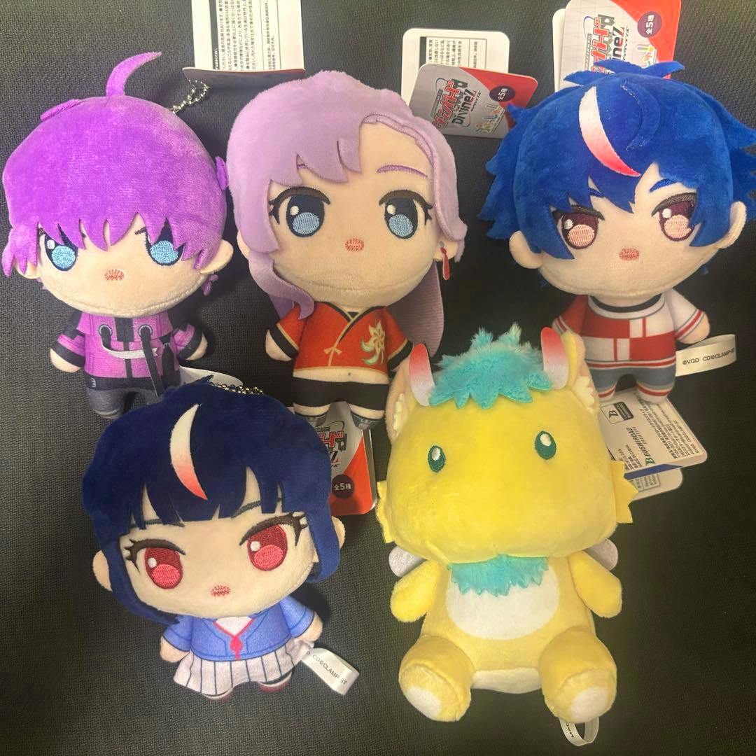 Five small plush mascot toys from Vanguard Divinez arranged on a dark background, showing four human-style characters and one yellow creature.