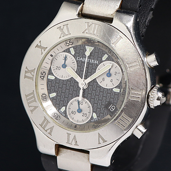 Close-up photo of a Cartier men's chronograph wristwatch with a black patterned dial, three subdials, date window, and a metal case with Roman numeral bezel.
