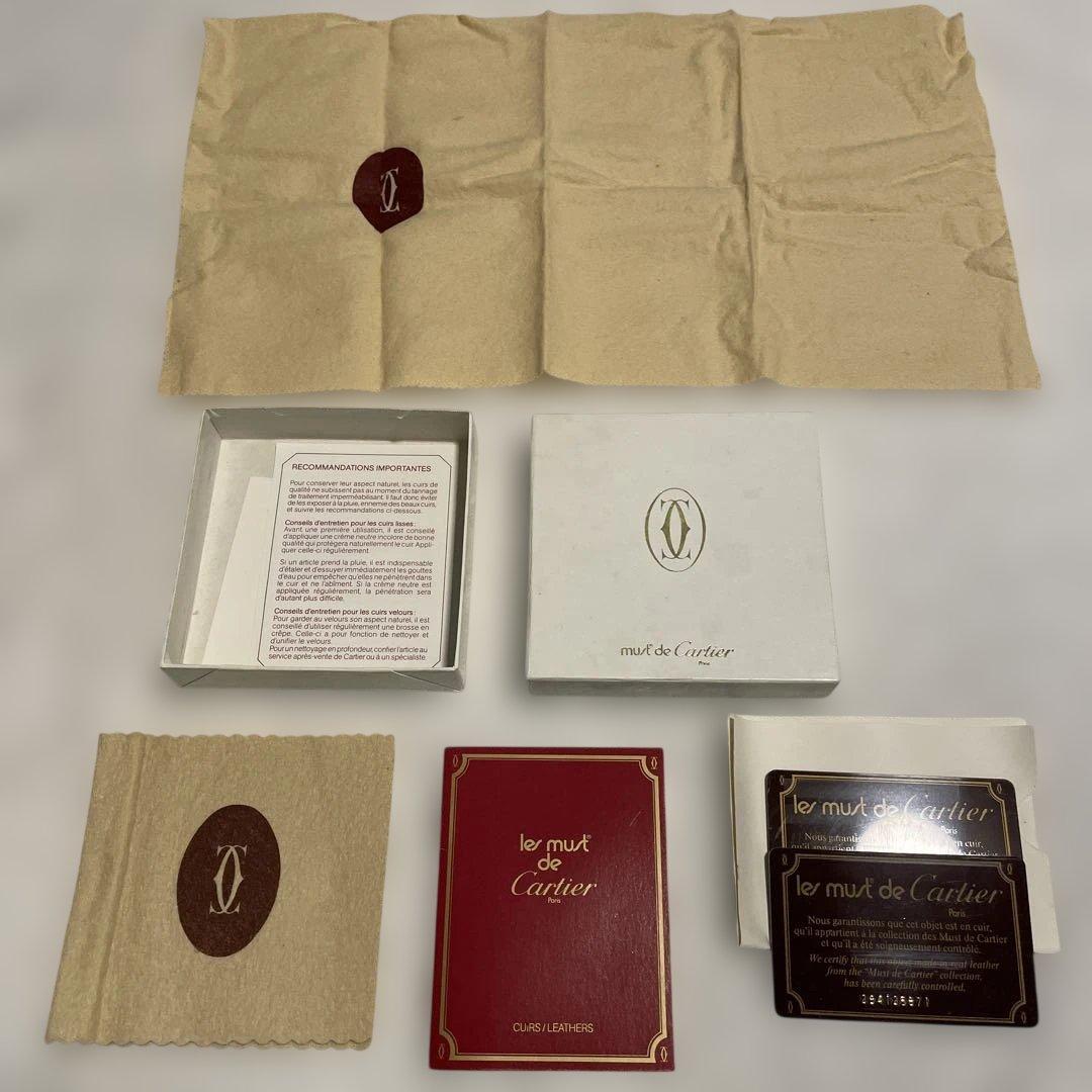 Empty Cartier gift box components arranged on a white background: box lid and base, tissue paper with Cartier logo, red booklet, cloth, and authentication cards.