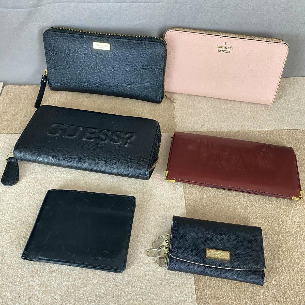 Several wallets and a key case in different colors laid out on a beige surface.