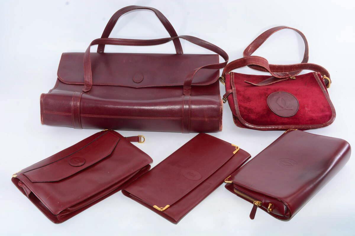 Five burgundy Cartier leather bags and clutches arranged on a white background.