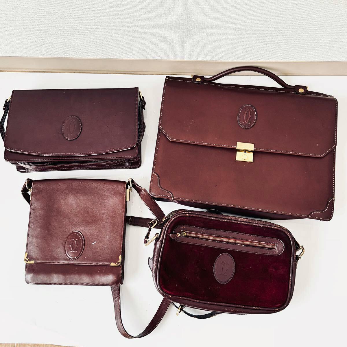 Four burgundy Cartier leather bags arranged on a white surface: one large top-handle bag and three smaller shoulder/crossbody bags.