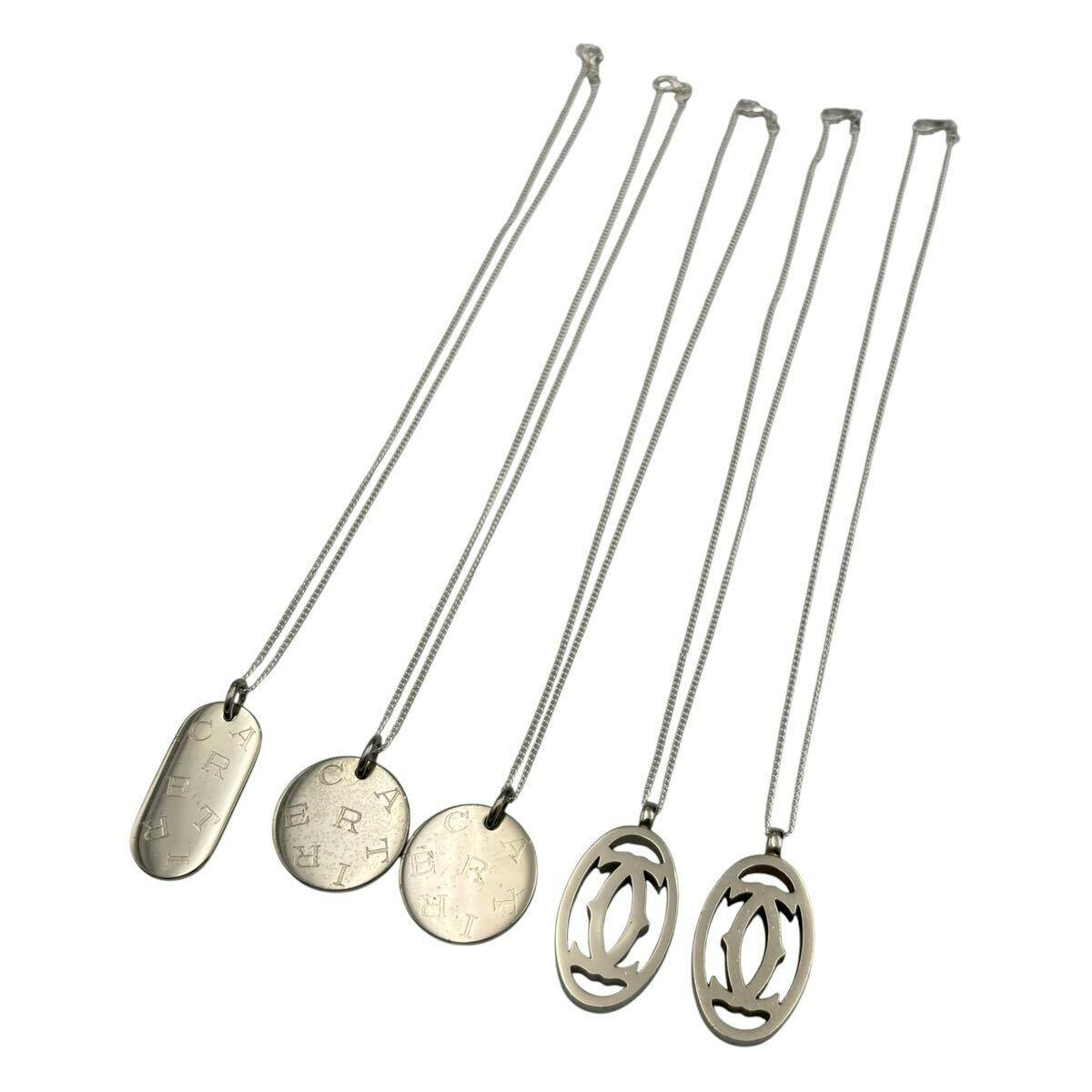 Five Cartier silver necklaces with various pendants (oval cutout, round, and plate styles) displayed on a white background.