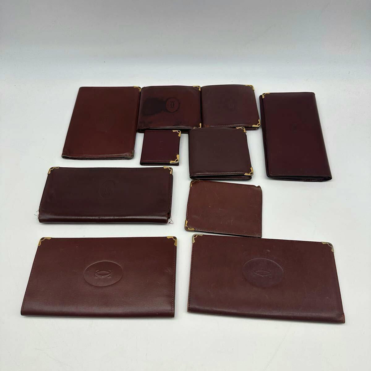 Multiple burgundy leather wallets and small coin purses arranged on a white background.