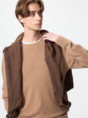 Model wearing a tan cashmere crew neck sweater with a brown sweater draped over his shoulders.