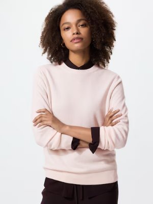 A model wearing a light pink cashmere crew-neck sweater.