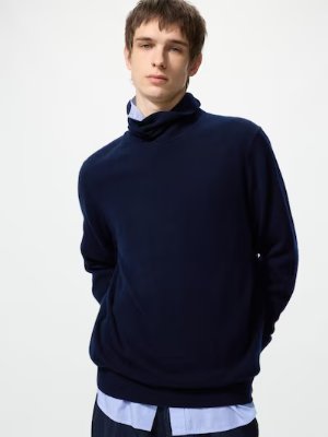 Male model wearing a navy cashmere turtleneck sweater over a light blue shirt.