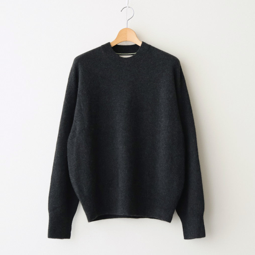 Charcoal cashmere crewneck sweater hanging on a wooden hanger against a white background.