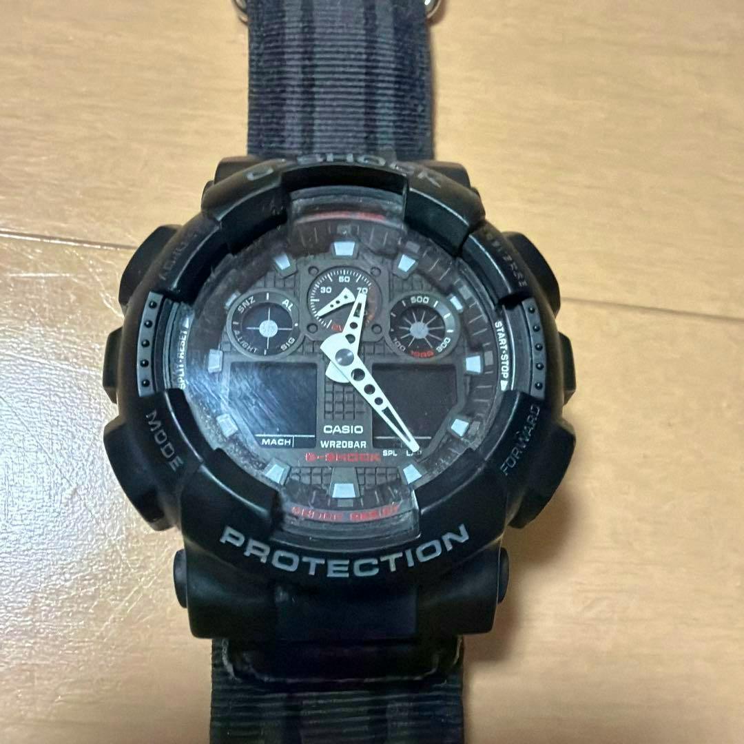 Top-down photo of a black CASIO G-SHOCK digital wristwatch showing the watch face and part of the strap on a wooden surface.