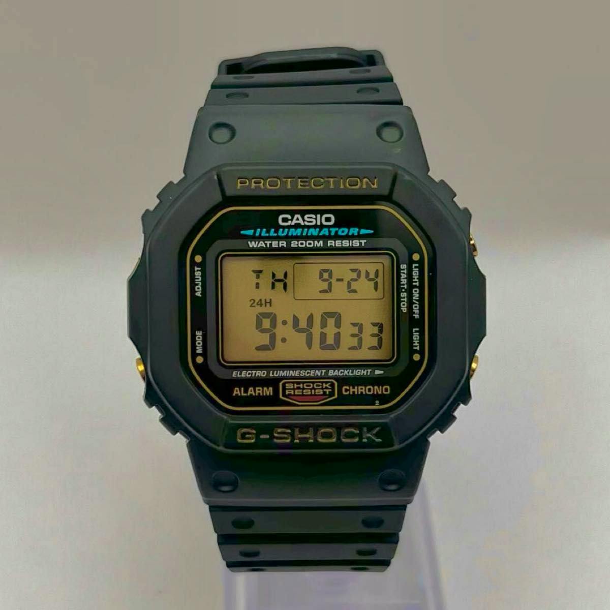 Front view of the CASIO G-SHOCK DW-5600EG-9V digital watch with a black resin case, gold-accented display, and black caterpillar-style strap.