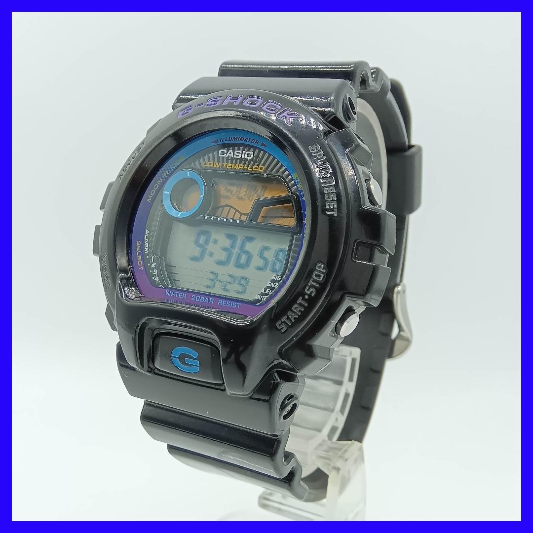 Three-quarter front view of a black Casio G-SHOCK G-LIDE digital watch on a clear display stand showing the face and strap.