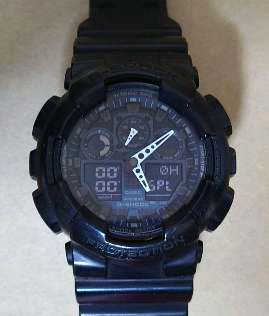 Front view of a black G-SHOCK GA-100-1A1JF wristwatch showing the dial and resin band.