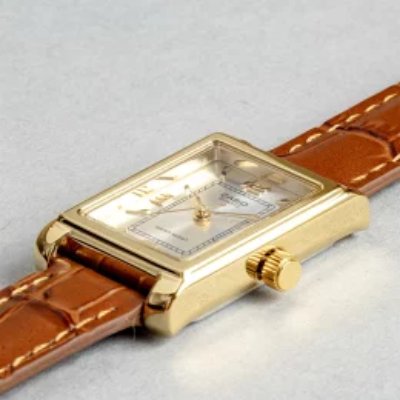 Close-up of the CASIO STANDARD WOMEN wristwatch with a rectangular gold-tone case and brown leather strap.