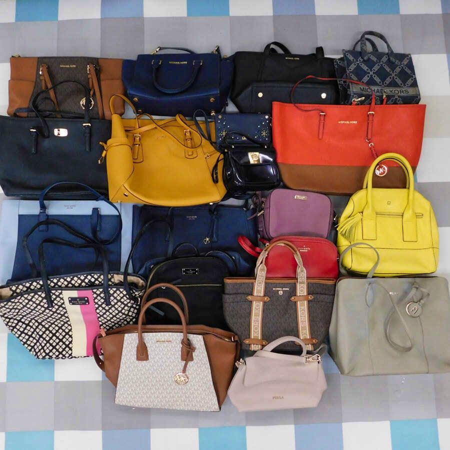Overhead photo showing about twenty casual handbags arranged on a tiled floor.