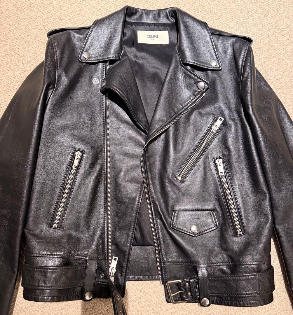 Black CELINE men's cow-leather rider's jacket laid flat showing front, zippers, lapels, and belt.