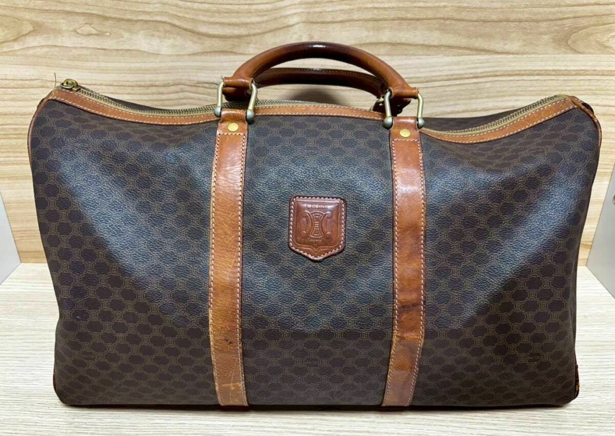 Front view of a CELINE brown macadam-pattern Boston bag with leather trim, handles, and a central logo patch.