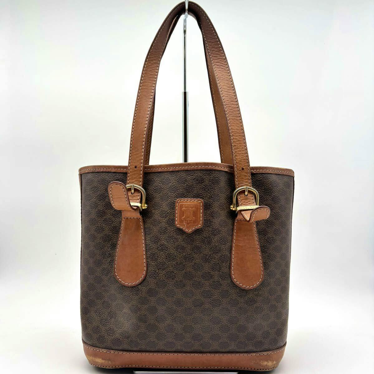 Front view of a brown CELINE bucket tote bag with macadam pattern and leather trim on a white background.