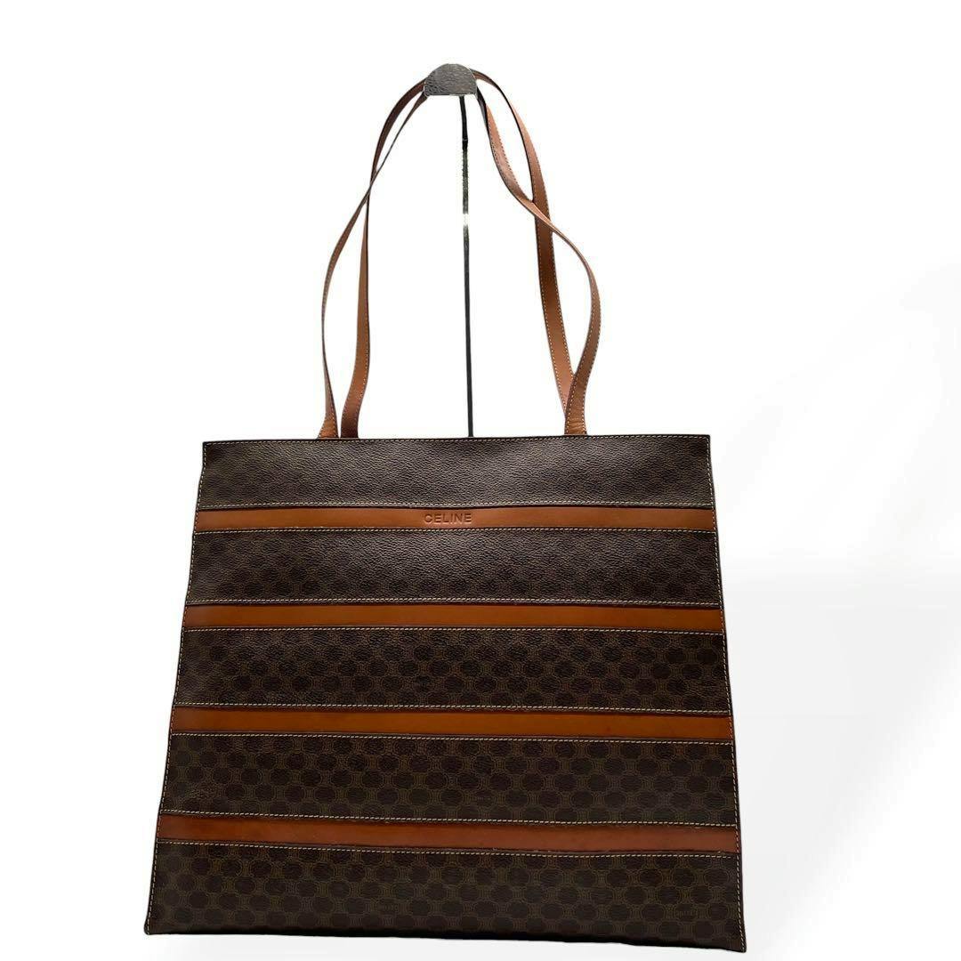 Brown CELINE canvas tote bag with macadam pattern, horizontal tan leather stripes, and shoulder straps photographed against a white background.