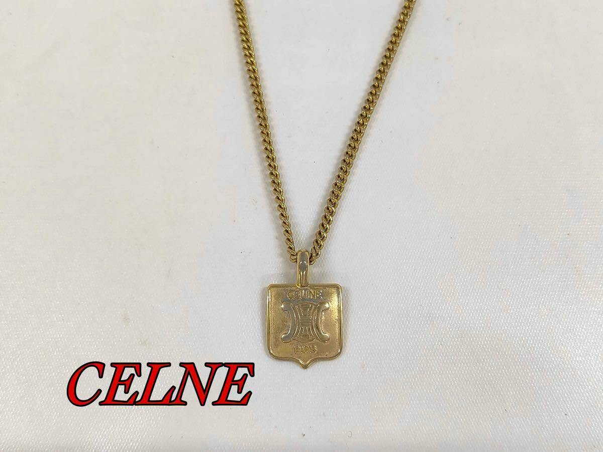 Gold-colored CELINE necklace with a shield-shaped logo pendant displayed on a white background.