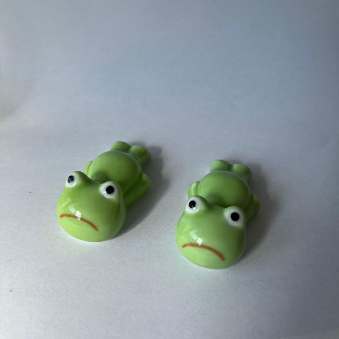 Two small green ceramic frog-shaped chopstick rests shown on a white background.