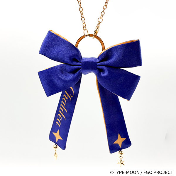 Photograph of a blue polyester ribbon charm with a gold ring and short chain, showing two hanging tails with gold star motifs and small dangling star charms.