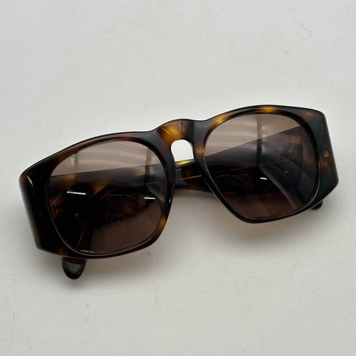 Tortoiseshell CHANEL sunglasses with brown lenses shown lying on a white background, front and top of the frames visible.