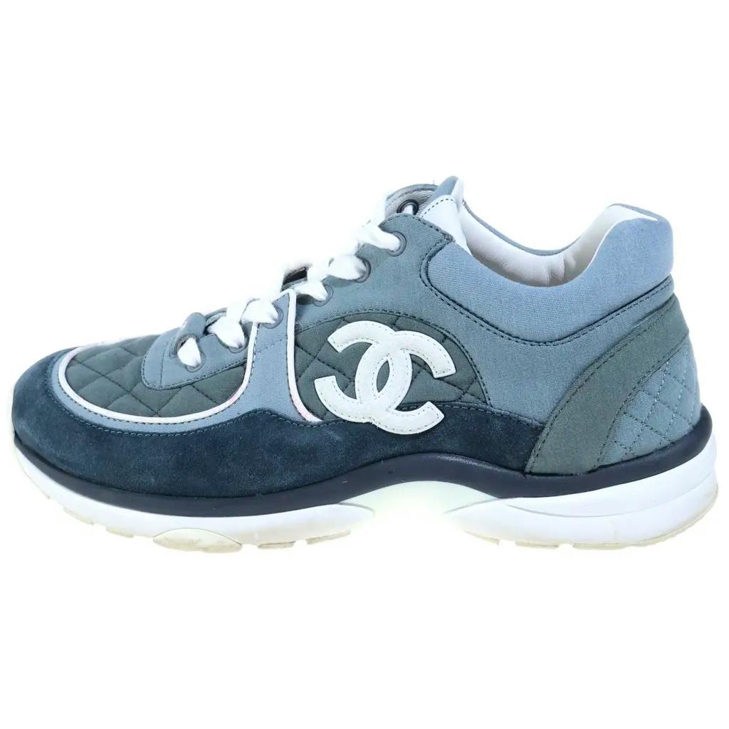 Side view of a gray Chanel low-cut sneaker with suede and quilted nylon panels and a white CC logo.