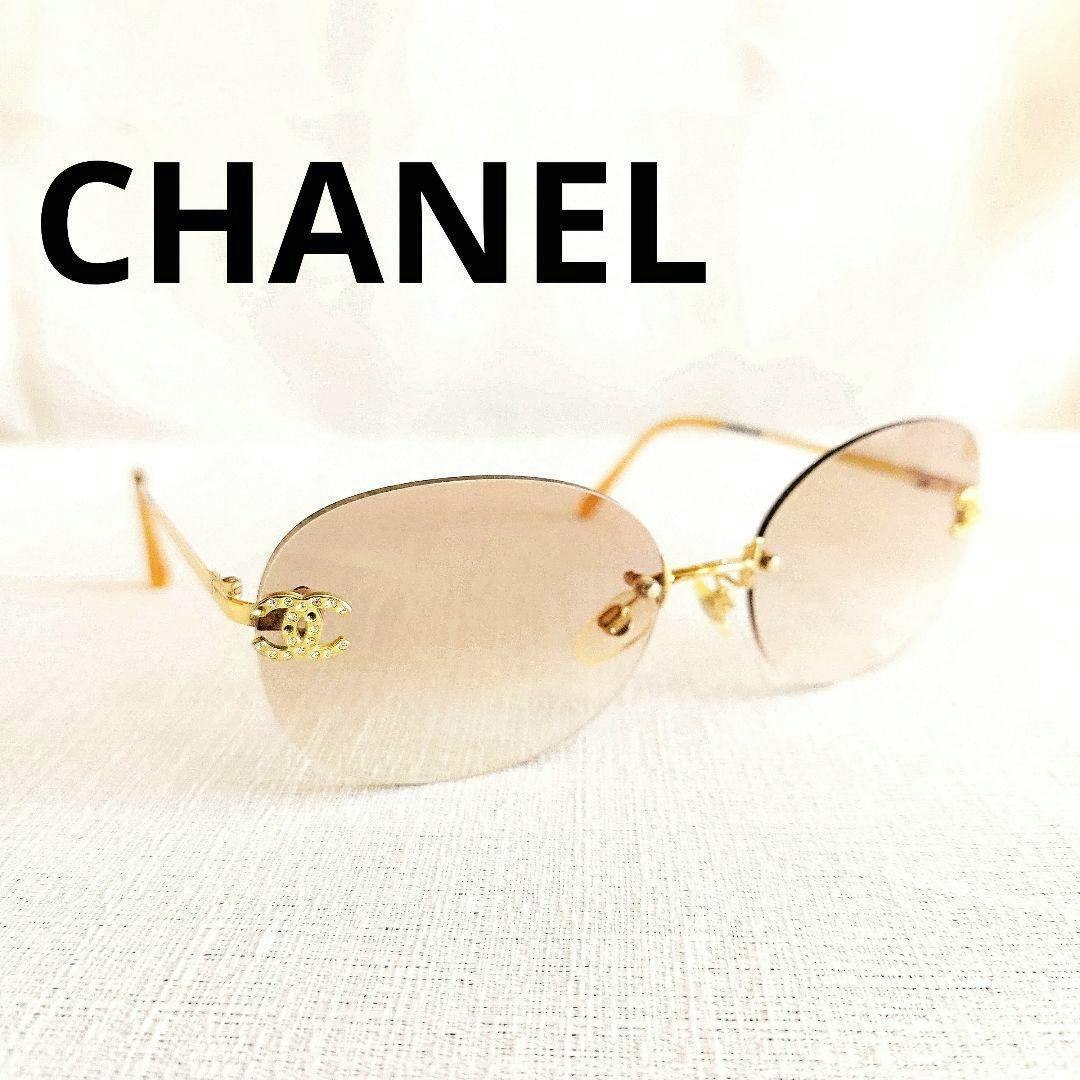 Rimless Chanel women's sunglasses with light gradient lenses and gold temples showing a CC logo with rhinestones, photographed on a light surface.